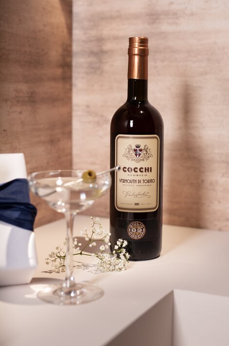 A bottle of Cocchi Vermouth against a pink and beige background. 