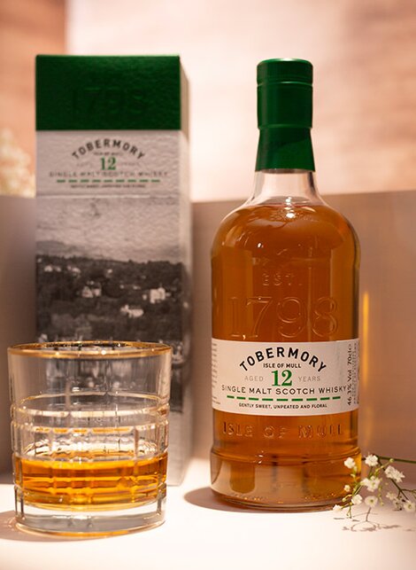 A bottle of Tobermory 12 year old whisky against a pink and beige background. 