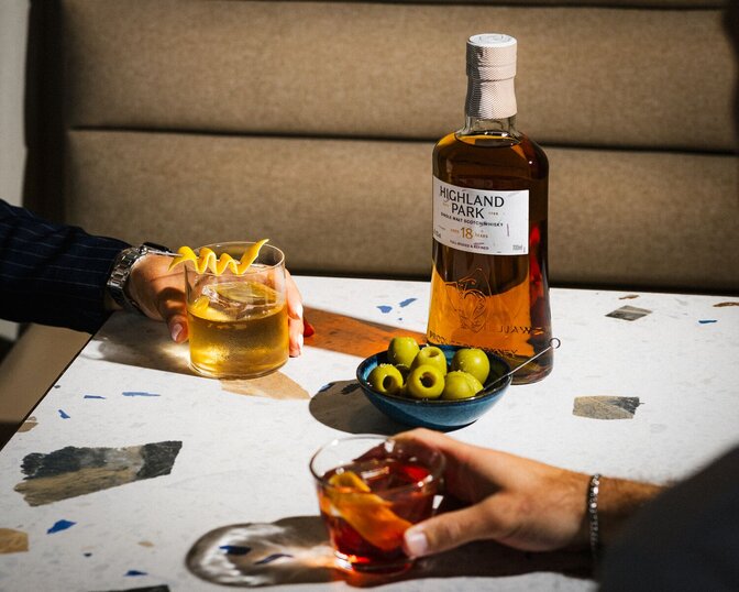 A bottle of Highland Park 12 Year Old on a party table with food and drink.