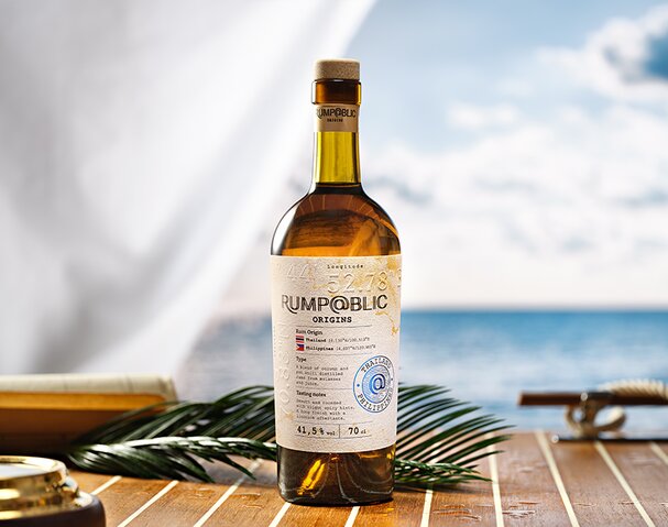 A bottle of Rump@blic Origins Thailand/Phillippines on a boat deck next to a branch. 