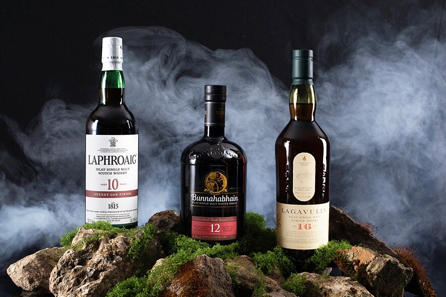 Caol Ila Moch whisky on a mossy rock surface surrounded by fog.
