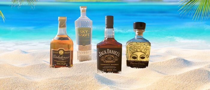 Bottles of Whisky, Gin, Rum and Tequila buried on a beach.