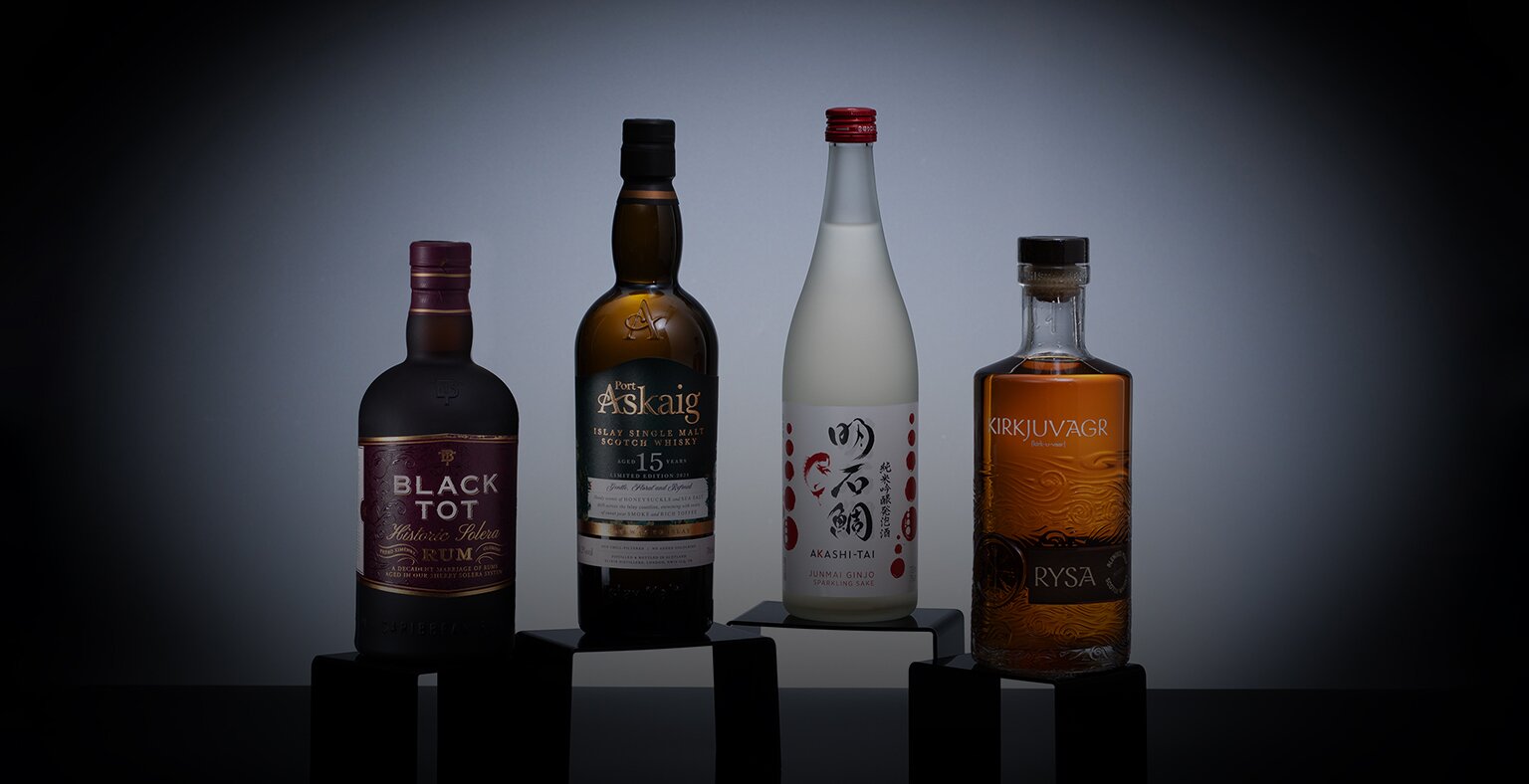 Four bottles of spirits on a black background with a spotlight.