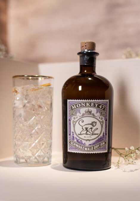 A bottle of Monkey 47 Dry Gin against a pink and beige background. 