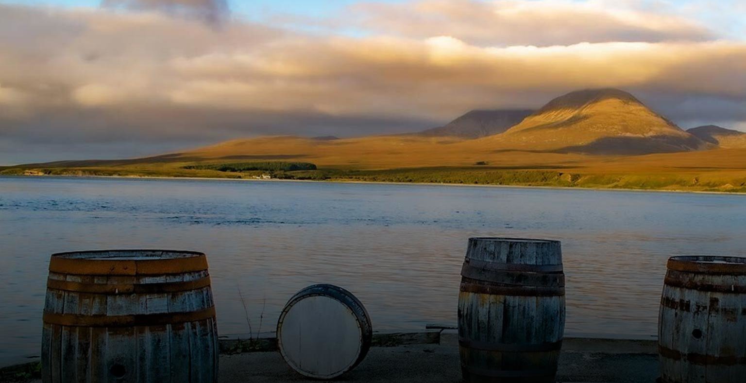 Whisky barrels facing the ocean with mountains in the background