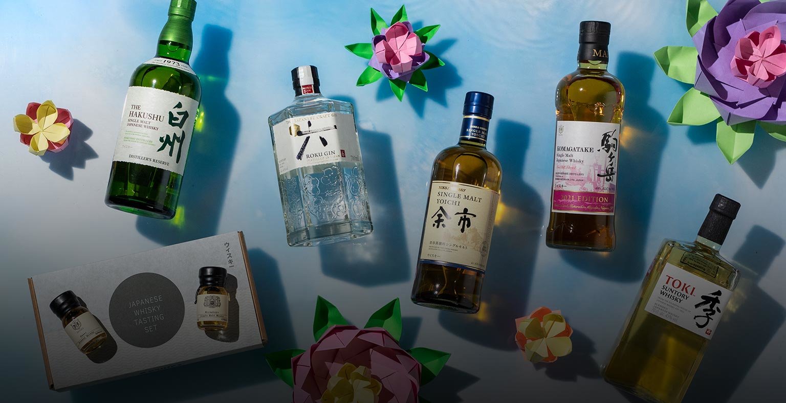 Bottles of Japanese spirits on a blue background with origami flowers