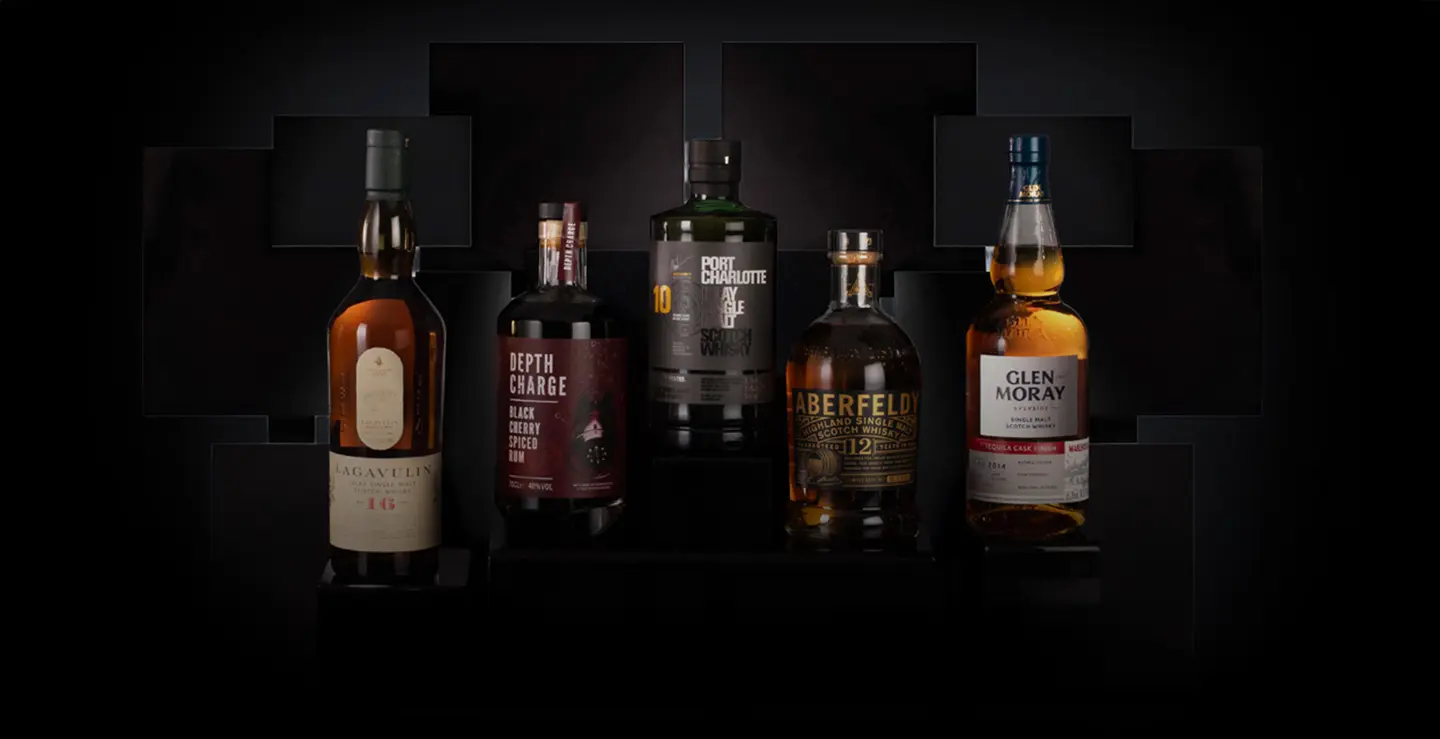 Five bottles of whisky and rum on a black background.
