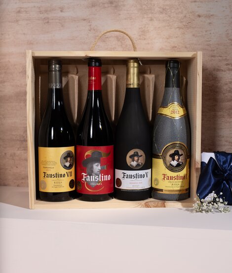 Four bottles of Faustino wine and a gift box against a pink and beige background. 
