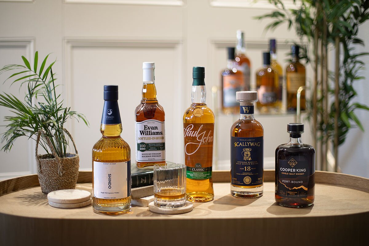 Bottles of whisky on a table next to plants. 
