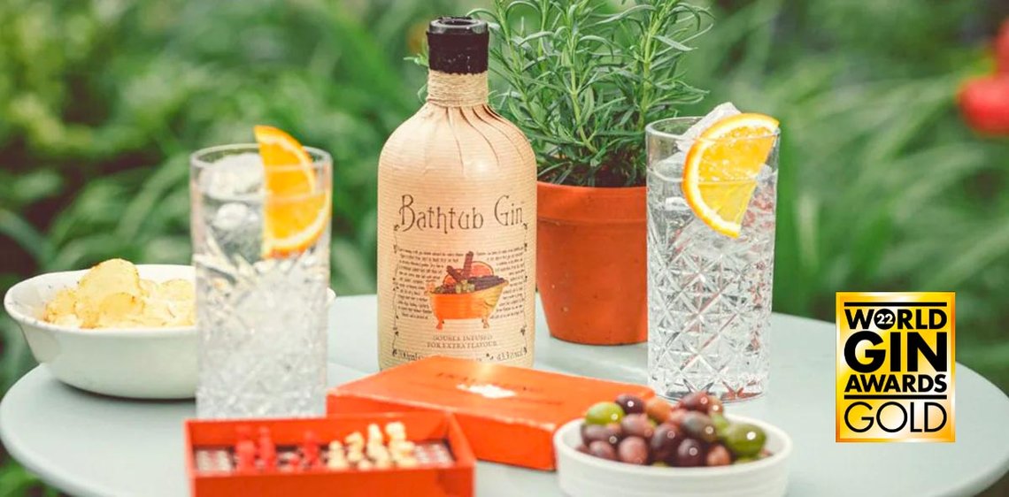 Bathtub Gin on a table outside, with two highball cocktails and lemon wedges. Awarded World Gin Gold 2022.