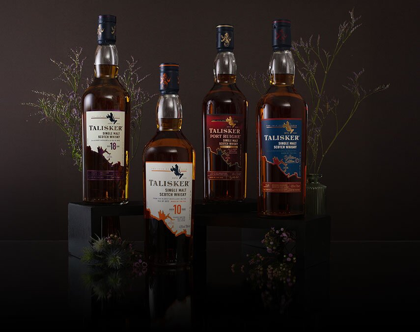 Four bottles of Talisker whisky surrounded by thistles on a brown background.
