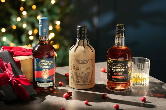Three bottles of rum with two glasses in a Christmas setting
