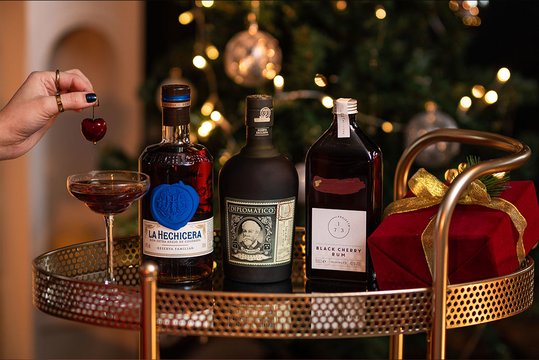 Three bottles of rum with two glasses in a Christmas setting