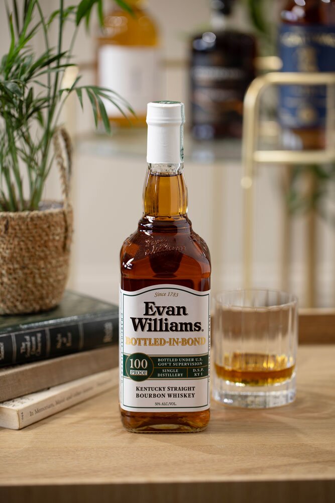 Evan Williams Bottled-in-Bond bourbon whiskey bottle with glass