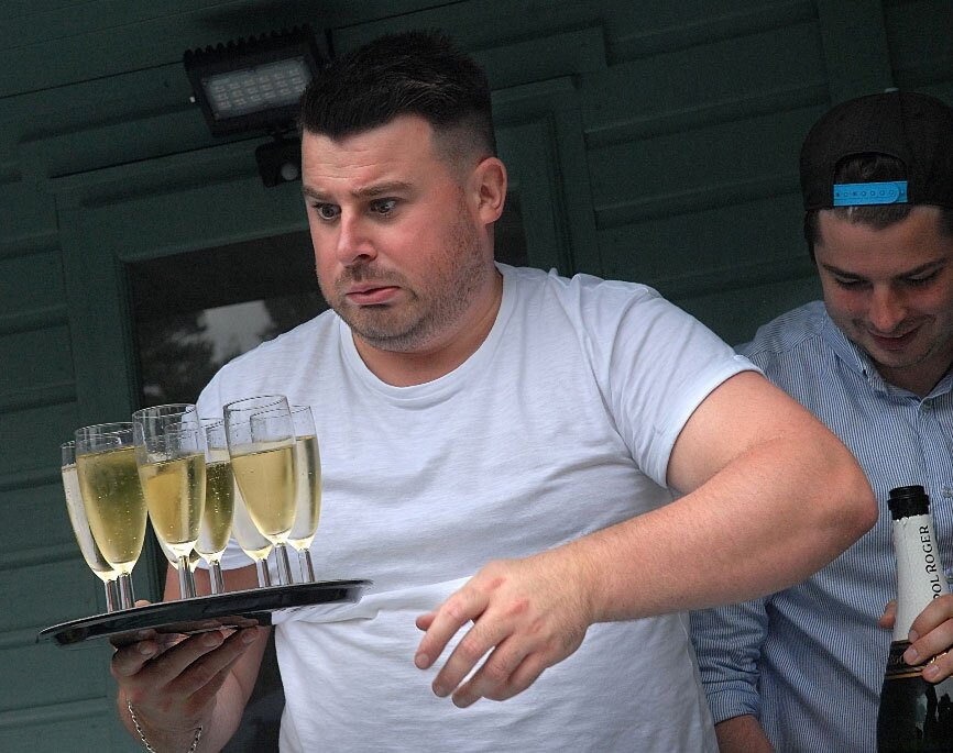 Mark tentatively carrying Champagne glasses