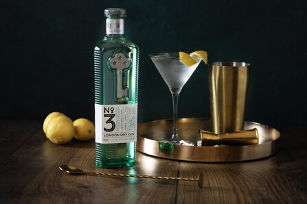 A bottle of No.3 Gin with a gin martini cocktail on the right of it.  