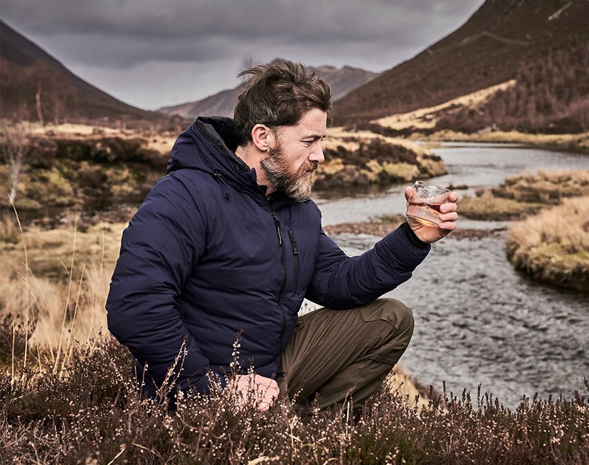 Aldo Kane holding a glass of whisky.