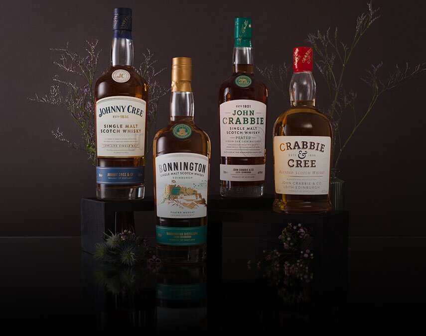 Four bottles of Bonnington whisky surrounded by thistles on a brown background.