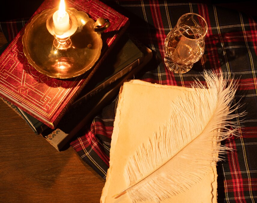 A feather, paper, quill and tartan.