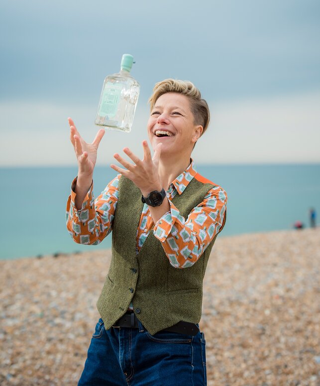Brighton Gin founder with a bottle of gin on the beach