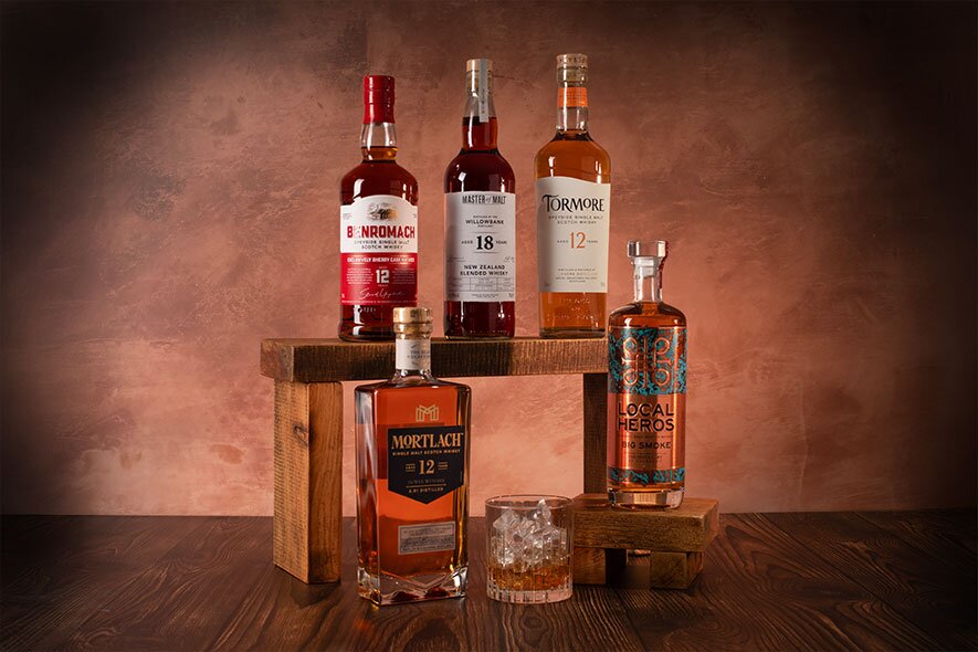 Five bottles of whisky on an orange background. 