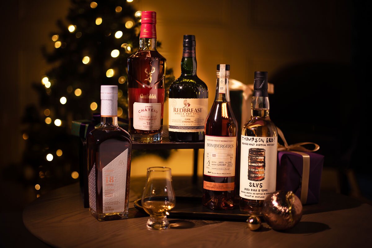 Five bottles of whisky in front of a Christmas tree.
