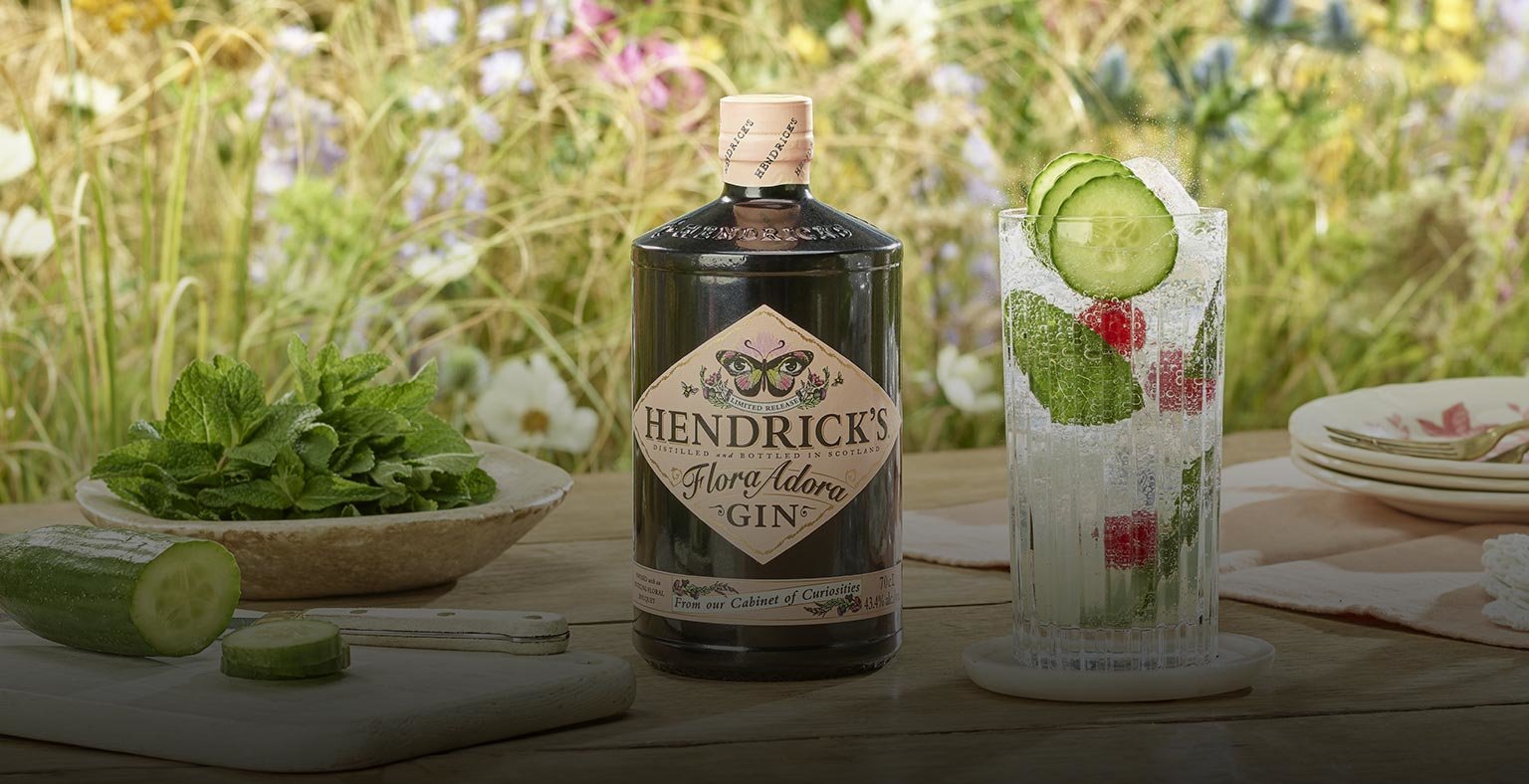 A bottle of Hendricks Flora Adora, a cocktail and garnishes on a table