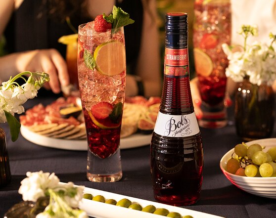 A Bols Strawberry Mojito with a bottle of Bols Strawberry Liqueur next to it.