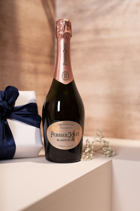 A bottle of Perrier-Jouet Blason Rose against a pink and beige background. 