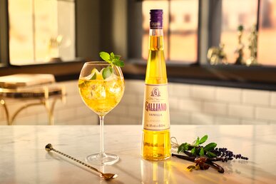 A Vanilla Spritz next to a bottle of Galliano Vanilla Liqueur.