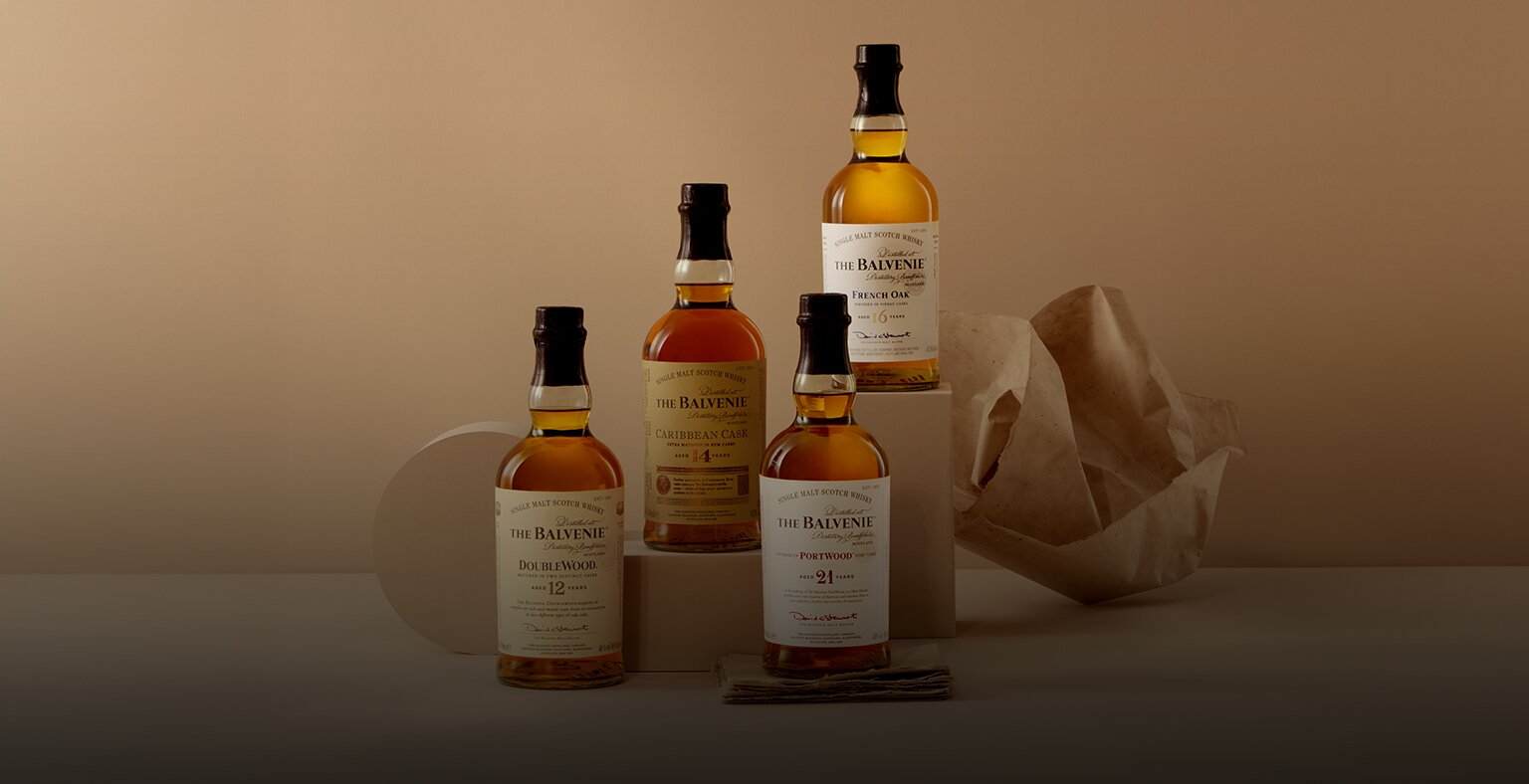 Four bottle of Balvenie whisky on a beige background.