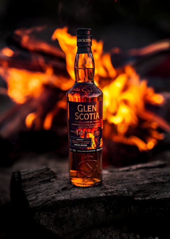 A bottle of Glen Scotia 14yo Icons #2 in front of a bonfire on the beach.