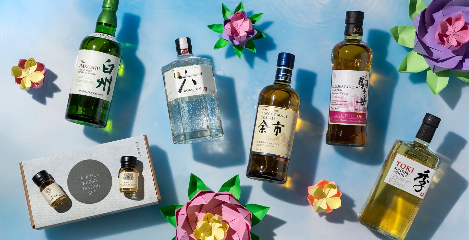 Bottles of Japanese spirits on a blue background with origami flowers