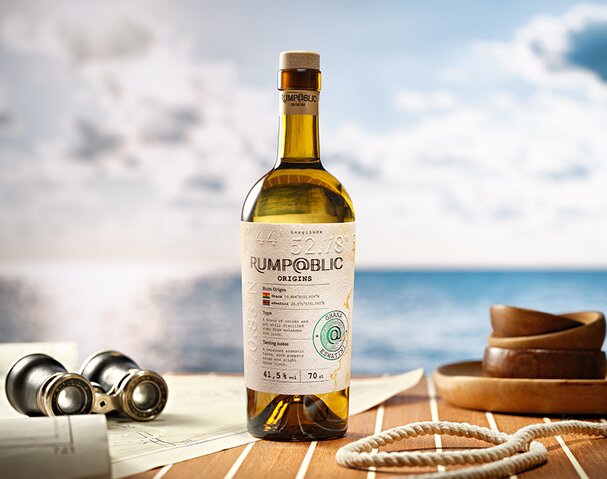 A bottle of Rump@blic Origins Ghana/Eswatini on a boat deck next to a pair of binoculars and rope. 