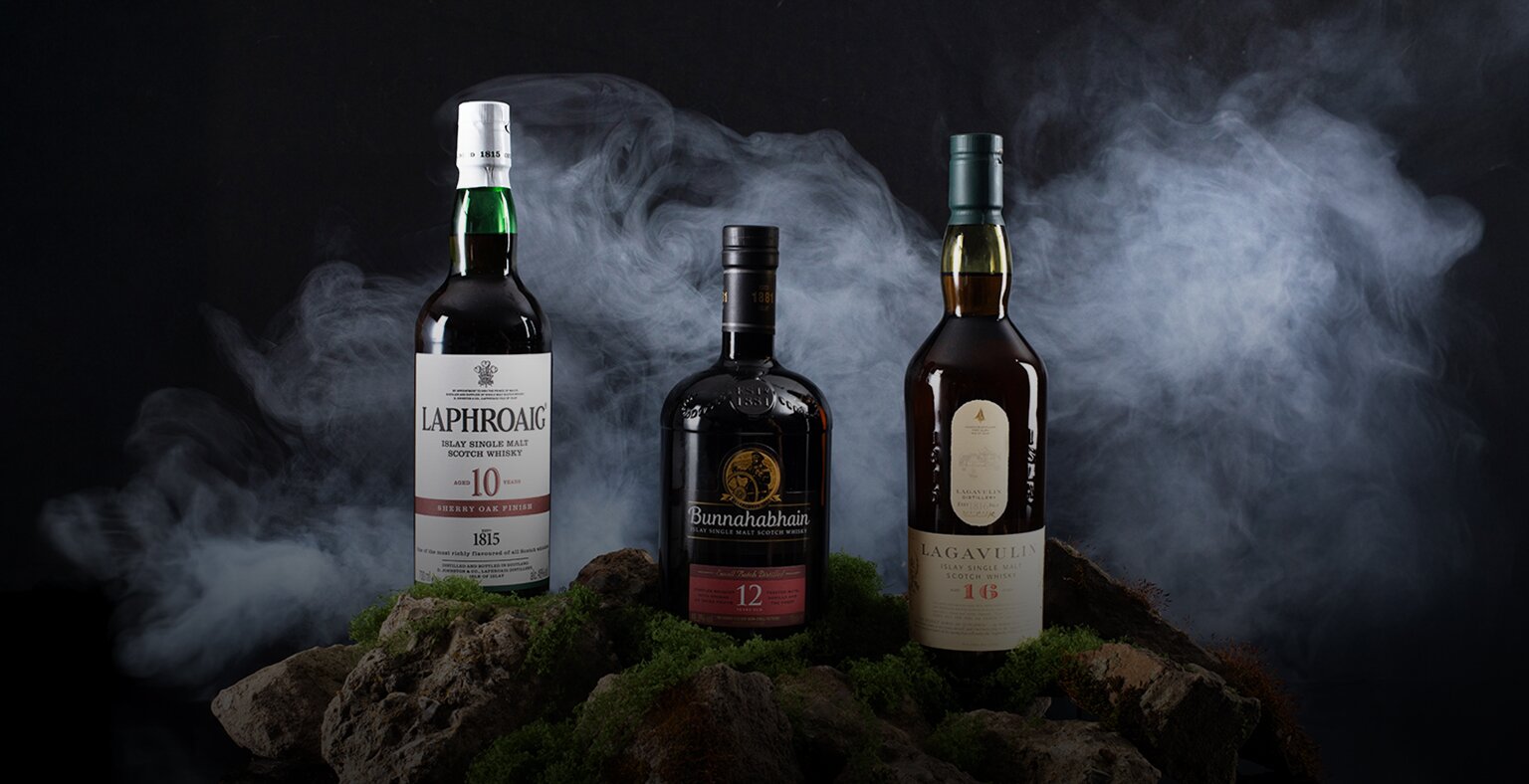 Three bottles of Islay Whisky; Laphroaig 10 Year Old Sherry Oak Finish, Bunnahabhain 12 Year Old, and Lagavulin 16 Year Old.