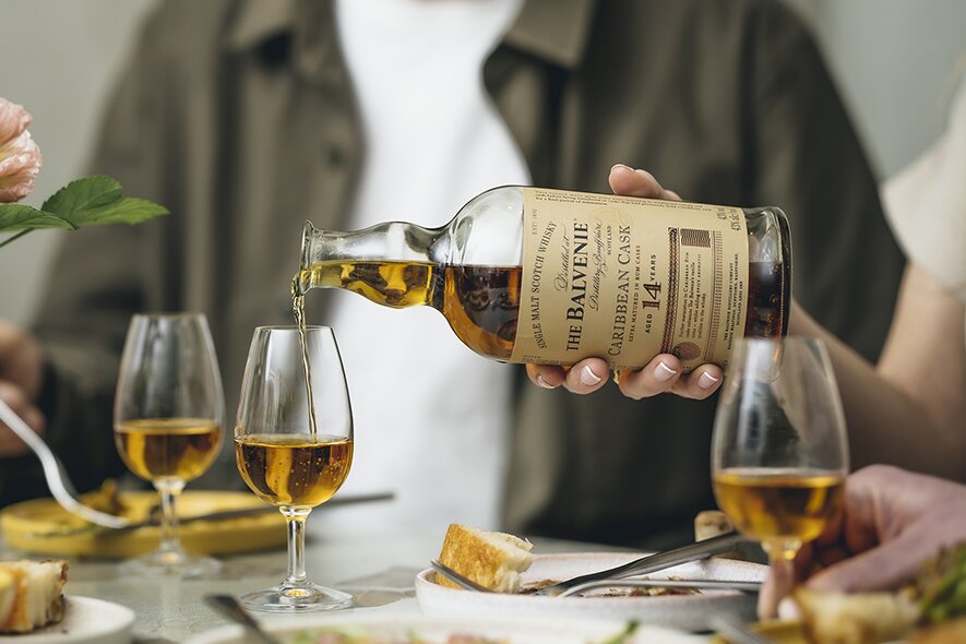 A bottle of Balvenie 14 Caribbean Cask being poured into tasting glasses. 