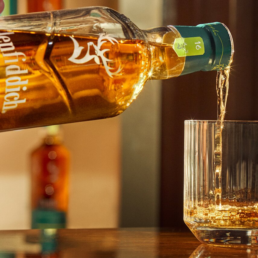 A bottle of Glenfiddich 16 Year Old x Aston Martin F1 being poured into a glass.