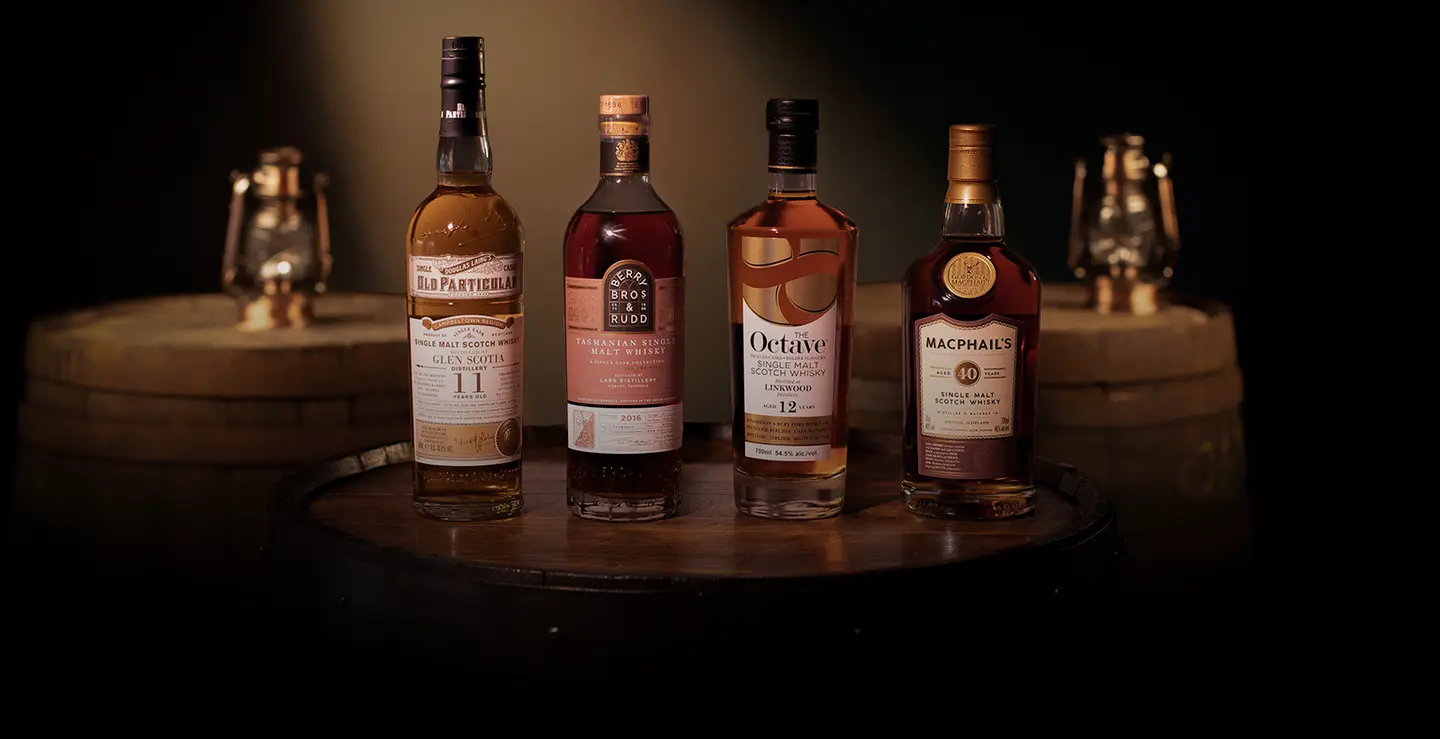 Four bottles of whisky on a cask background