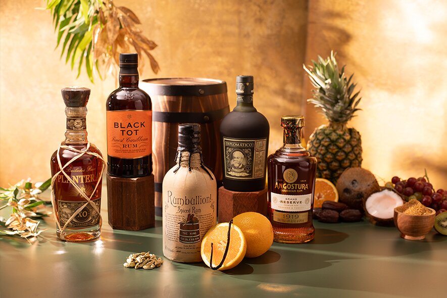 bottles of rum against a golden background with assorted fruit
