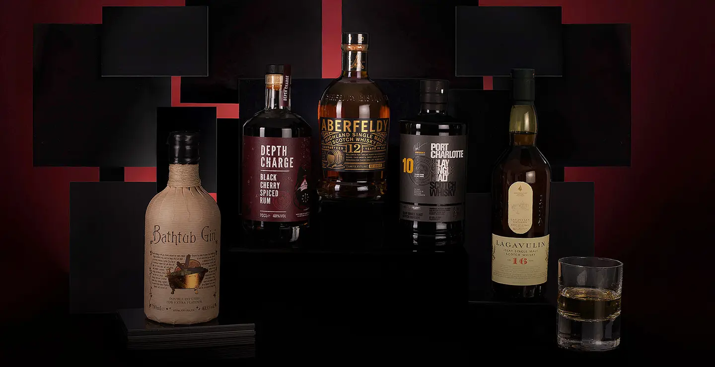 Five bottles of whisky and rum on a black background.