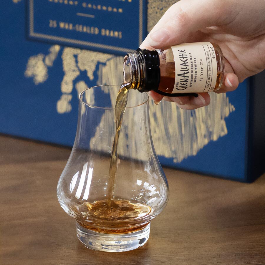 A whisky dram being poured in front of a Scotch Whisky advent calendar