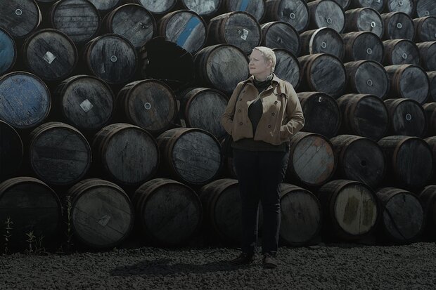 Woman standing in front of stacked Whisky barrels.