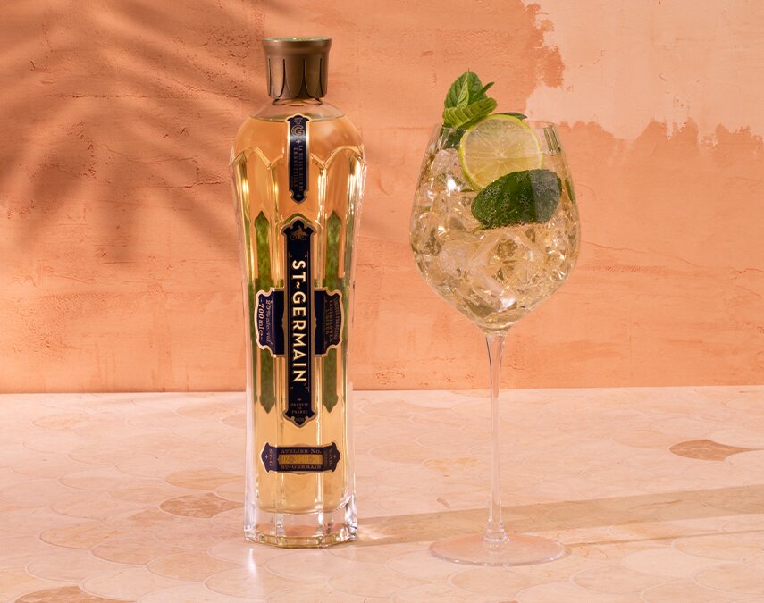 A bottle of St-Germain Elderflower Liqueur with four Hugo Spritz cocktails around it.