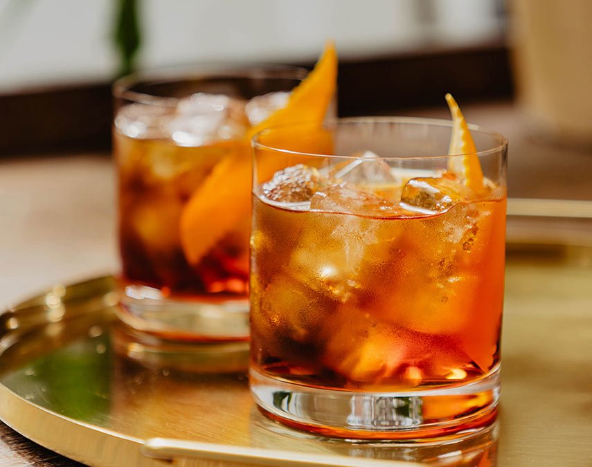 Old Fashioned cocktails with orange peel garnishes.