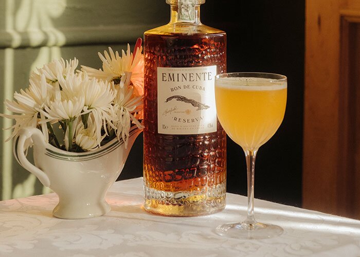 A bottle of Eminente Reserva 7 Year Old and dark daquiri cocktial.