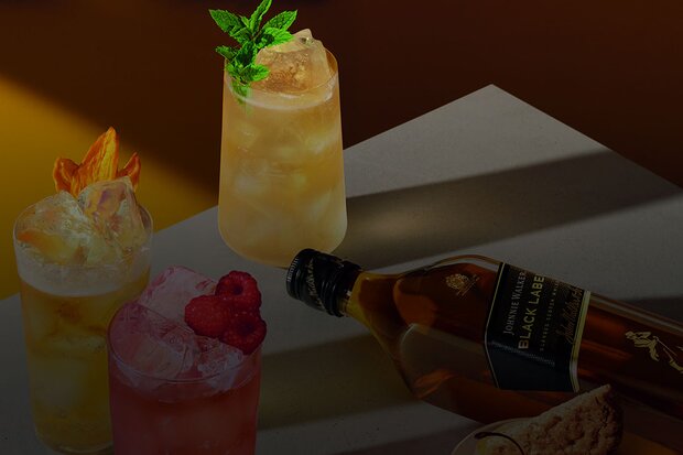 Johnnie Walker black label, surrounded by bright coloured Whisky highball cocktails.