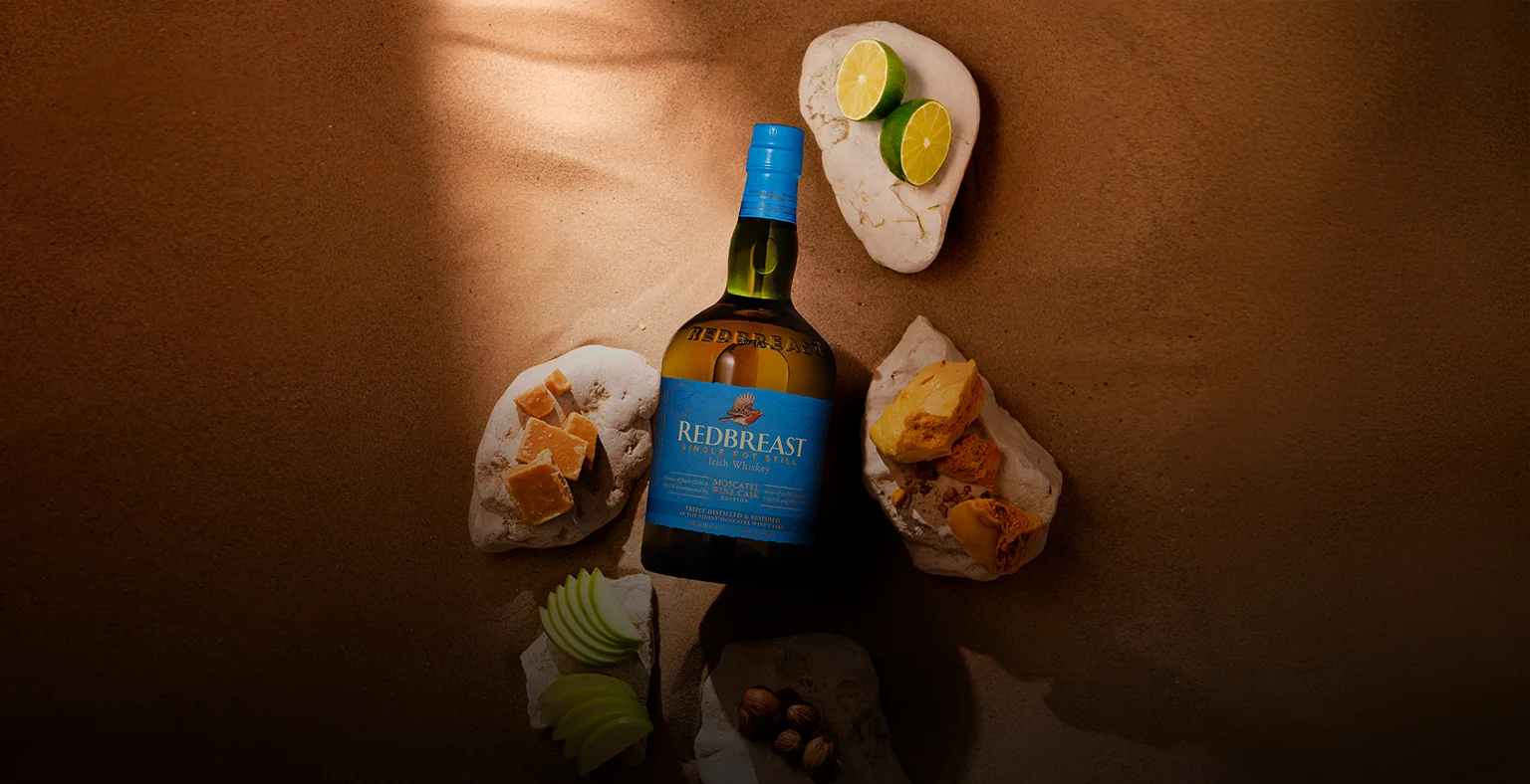 A bottle of Redbreast Moscatel laying on the sand surrounded by tasting notes.