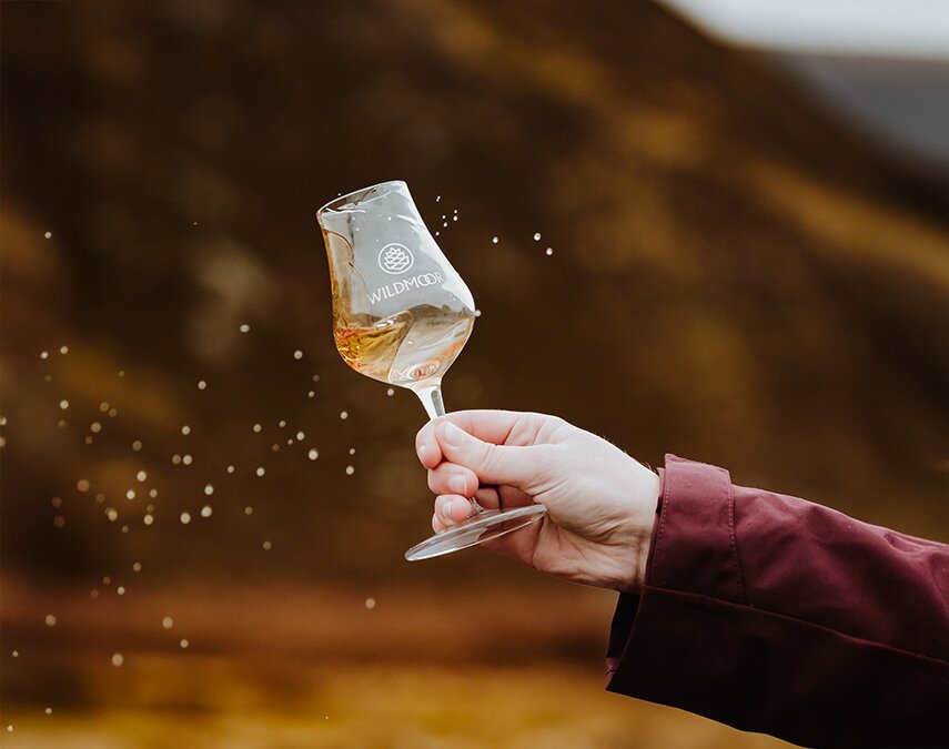 A woman holding a Wildmoor glass full of whisky.