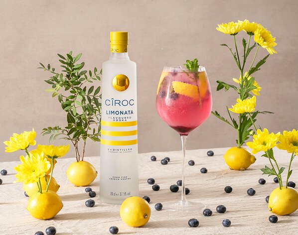 A Cîroc Limonata and Blueberry Spritz with a bottle of Cîroc Limonata on the left of it. 