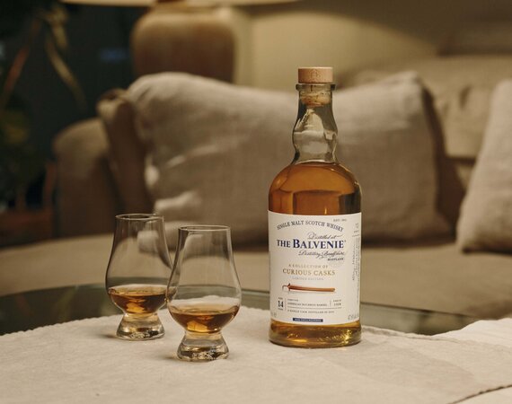 A bottle of The Balvenie Stories 14 year old Bourbon Barrel and 2 glasses of whisky.